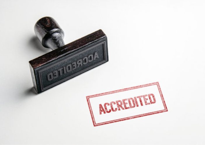 A rubber stamp and its "Accredited" imprint on paper