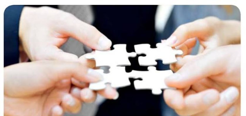 Four pairs of hands joining jigsaw pieces together
