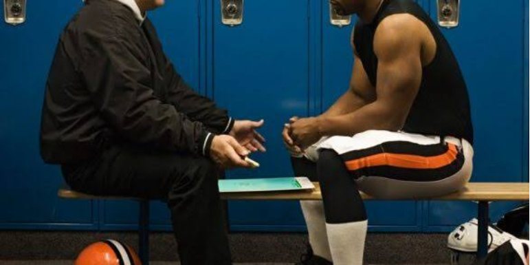 A coach talking with an athlete in a locker room