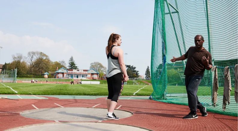 A coach giving feedback to an athlete on an athletics track