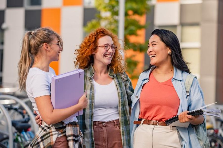 Three students talking and laughing together on campus