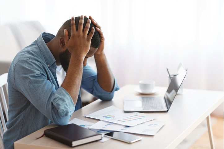 A manager sitting at a desk with their head in their hands